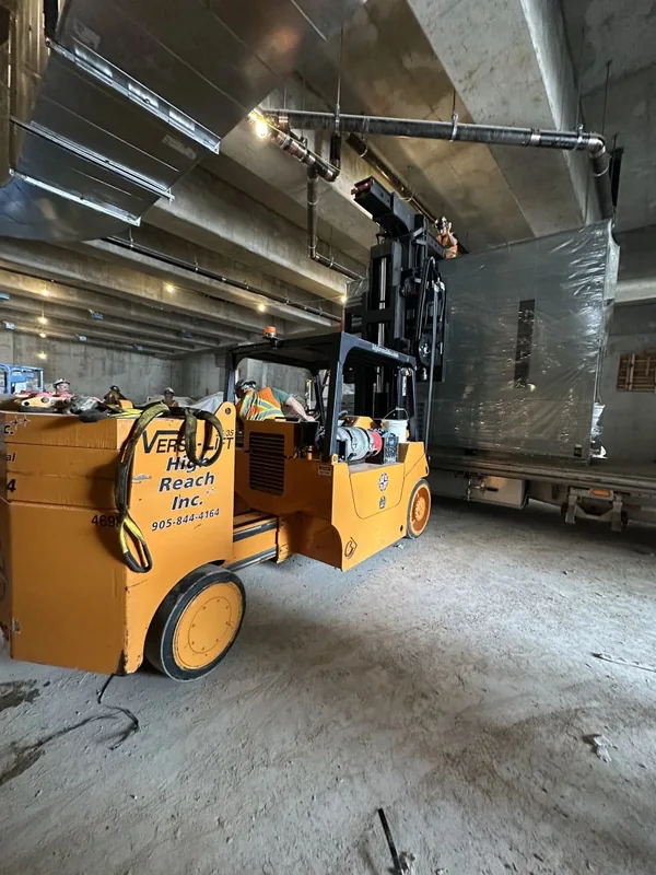 Versa lift taking a crated transformer off the flatbed