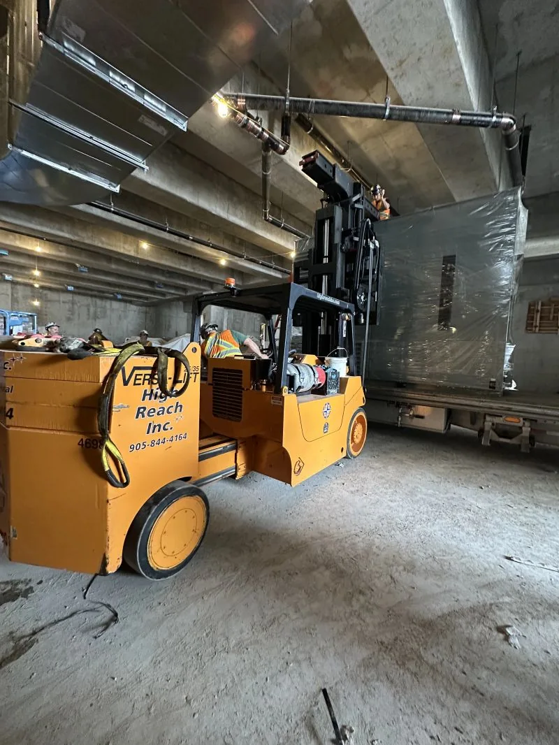 Versa lift taking a crated transformer off the flatbed